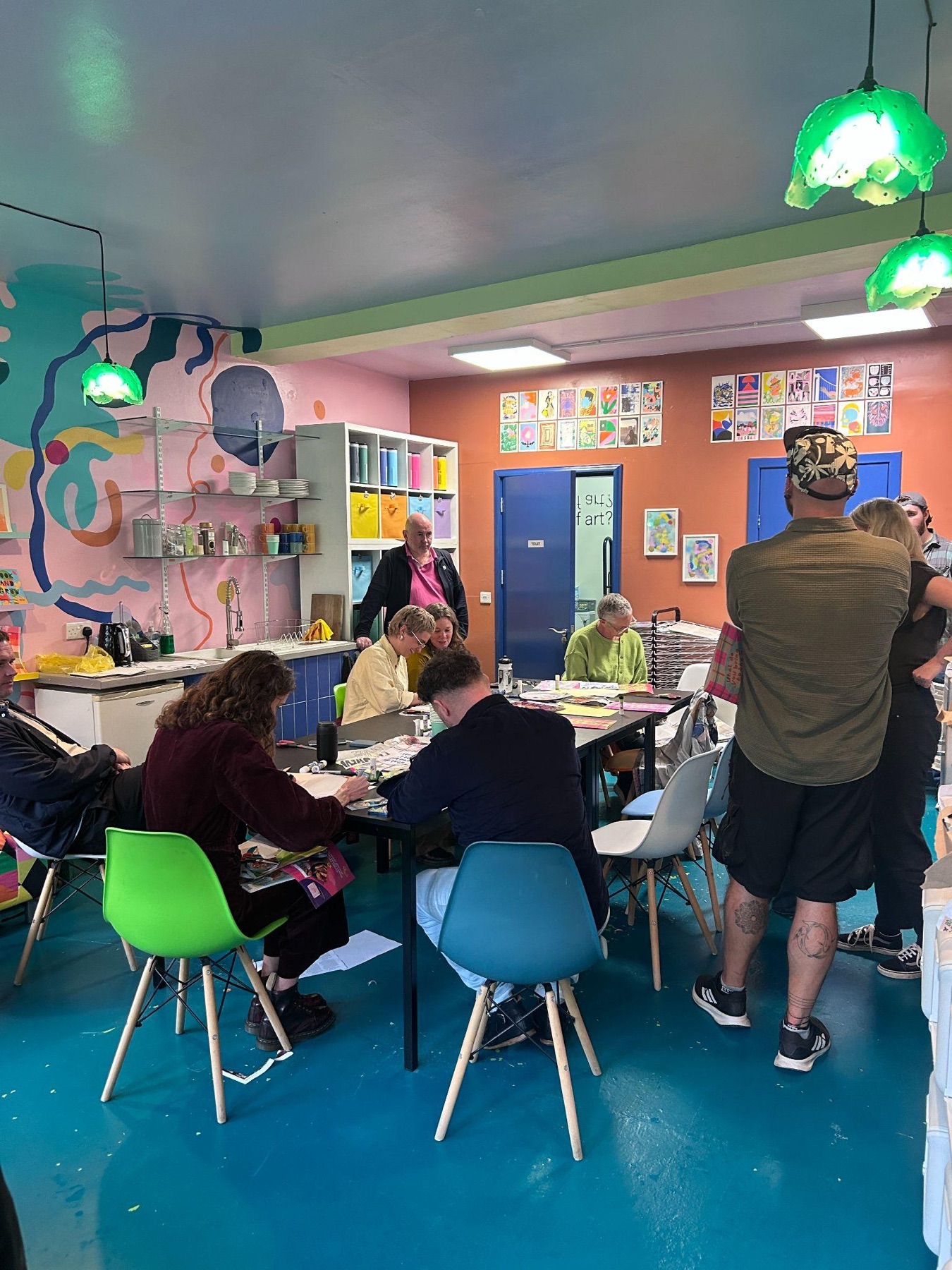 Participants working at tables in Narture's brightly painted print studio, with prints pinned along the wall